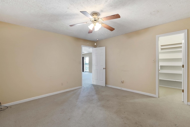 carpeted spare room featuring baseboards, a textured ceiling, and ceiling fan