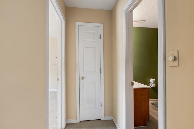 hallway featuring light colored carpet and baseboards