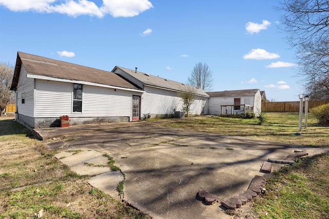 back of house featuring central air condition unit, a lawn, and fence