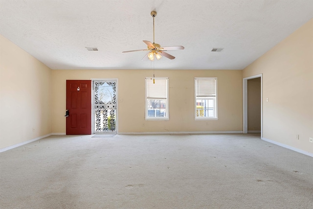 spare room with visible vents, baseboards, light carpet, a textured ceiling, and a ceiling fan