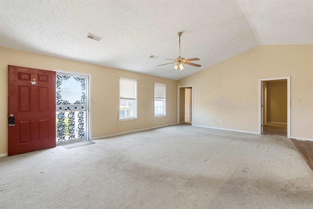 carpeted empty room with visible vents, lofted ceiling, a textured ceiling, and a ceiling fan