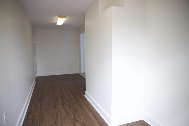 corridor featuring baseboards, dark wood-type flooring, and ornamental molding