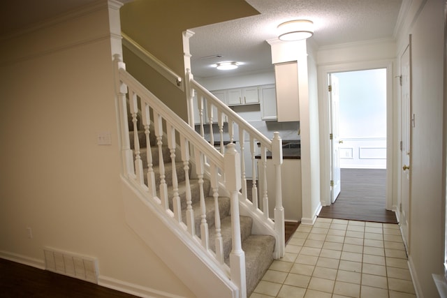 stairway with tile patterned floors, baseboards, visible vents, and a textured ceiling