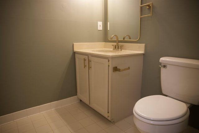 half bath featuring vanity, tile patterned floors, toilet, and baseboards