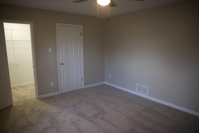 unfurnished bedroom featuring visible vents, a walk in closet, baseboards, carpet, and a closet