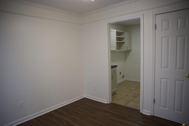 clothes washing area featuring baseboards, dark wood finished floors, and crown molding