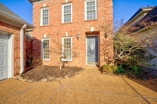 doorway to property with a garage and brick siding