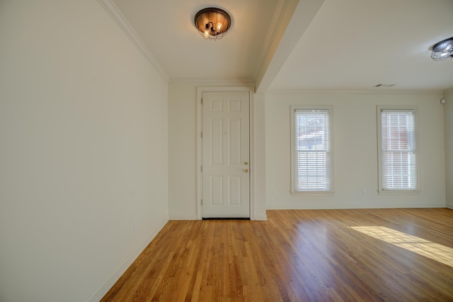 foyer entrance with light wood finished floors, baseboards, and ornamental molding