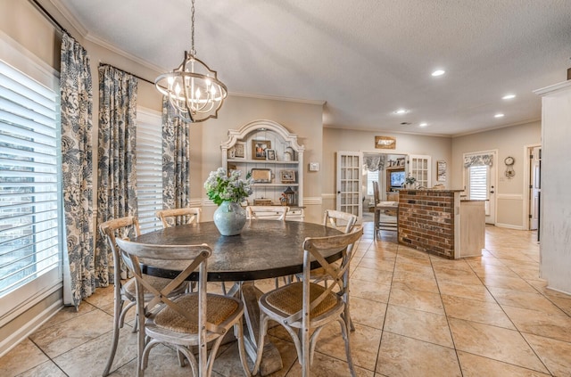 dining space with a textured ceiling, ornamental molding, light tile patterned floors, and a chandelier