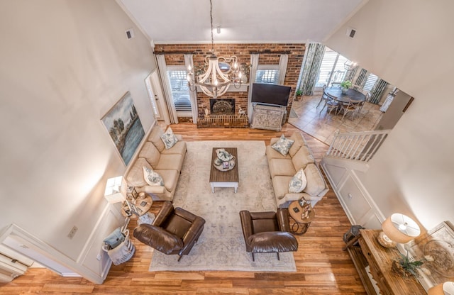 living room with visible vents, wood finished floors, a brick fireplace, and a chandelier