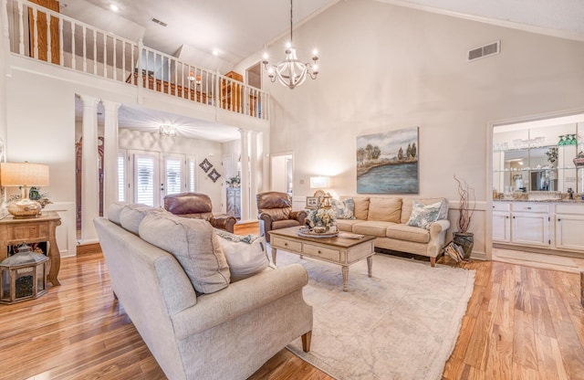 living room with visible vents, light wood finished floors, high vaulted ceiling, decorative columns, and a chandelier