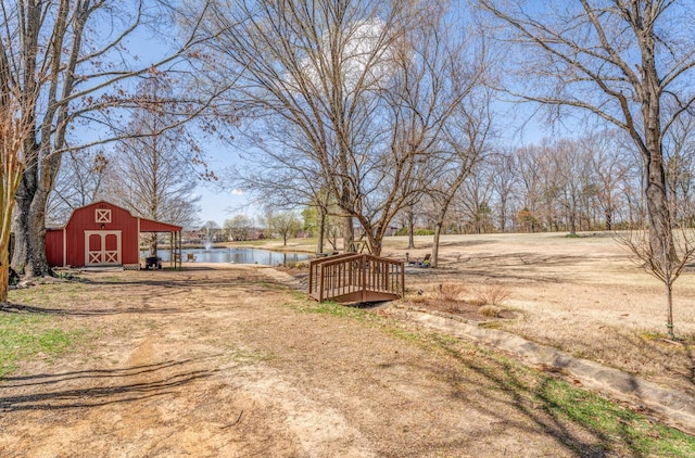 view of yard featuring a barn, an outdoor structure, and a water view