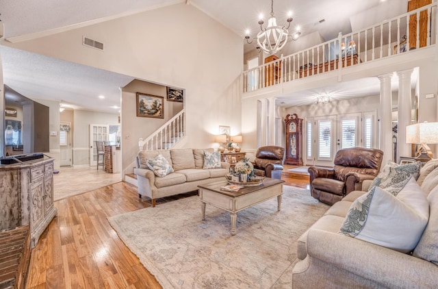 living room with visible vents, high vaulted ceiling, stairs, and light wood finished floors