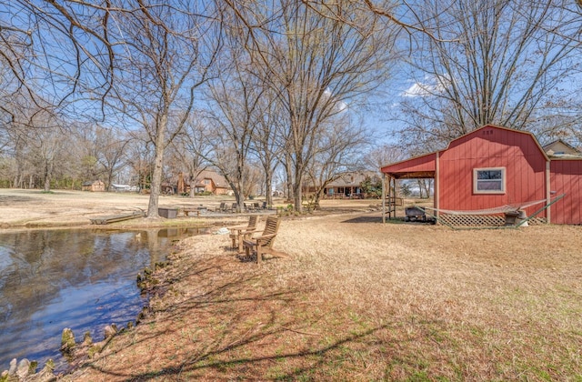 view of yard featuring an outbuilding, a barn, a water view, and a carport