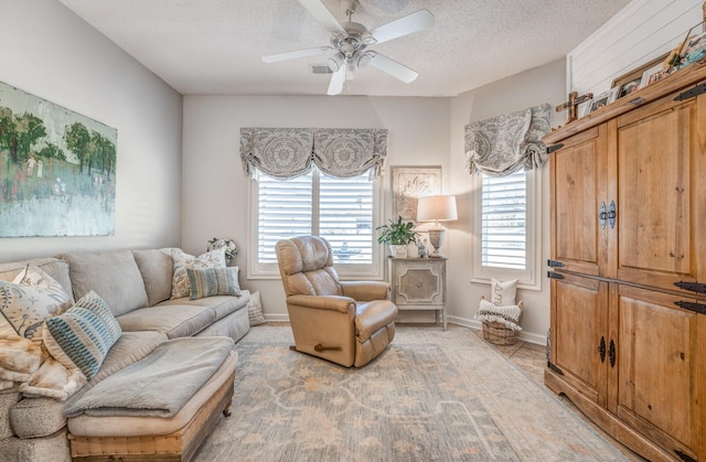 living room featuring baseboards, a textured ceiling, and a ceiling fan