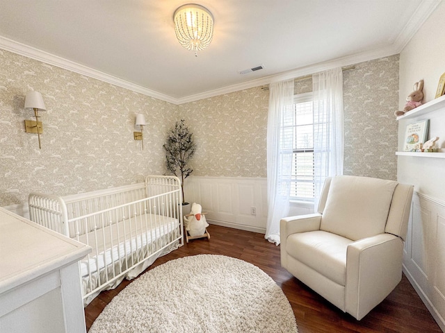 bedroom featuring a wainscoted wall, visible vents, wood finished floors, crown molding, and wallpapered walls