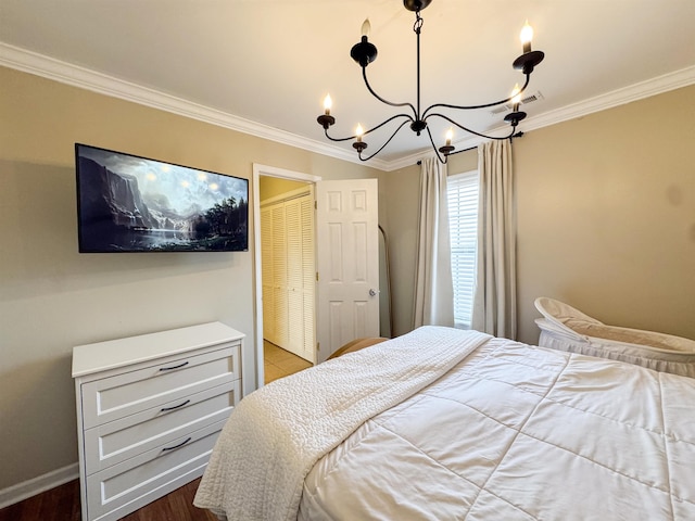 bedroom featuring dark wood-type flooring, baseboards, a chandelier, ornamental molding, and a closet