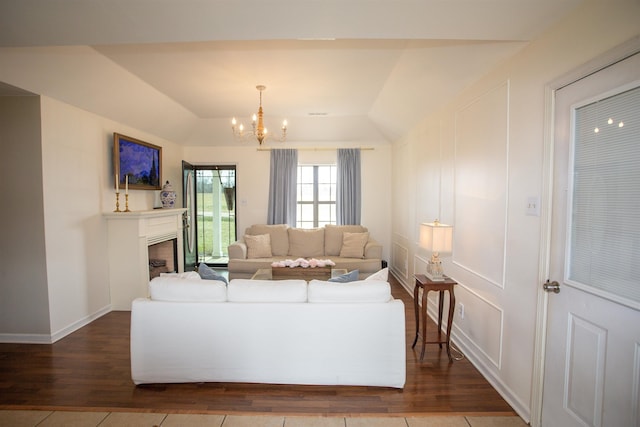 living room with dark wood-type flooring, a fireplace, baseboards, and a chandelier