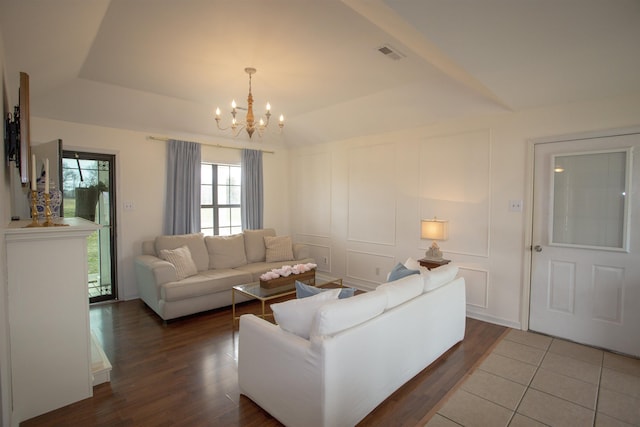 living area with an inviting chandelier, a decorative wall, wood finished floors, and visible vents