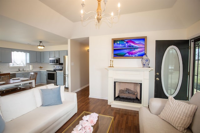 living area with dark wood finished floors, an inviting chandelier, a fireplace, and baseboards