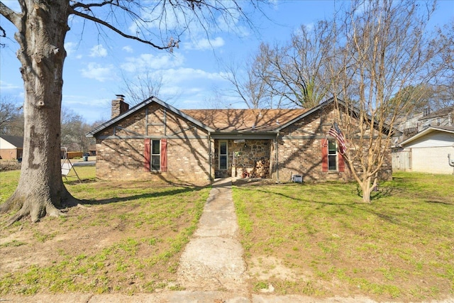 view of front of house featuring brick siding, a chimney, and a front yard