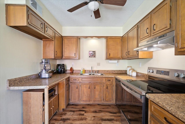 kitchen featuring under cabinet range hood, brown cabinets, stainless steel range with electric stovetop, and a sink