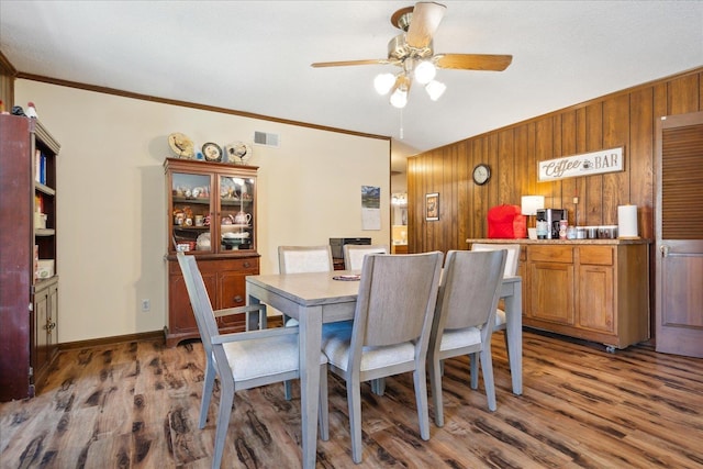 dining room with wood finished floors, baseboards, visible vents, ornamental molding, and ceiling fan