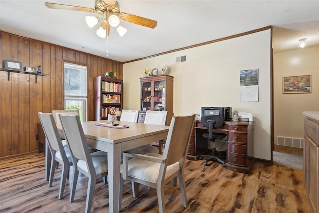 dining space featuring visible vents, a textured ceiling, wood finished floors, and a ceiling fan