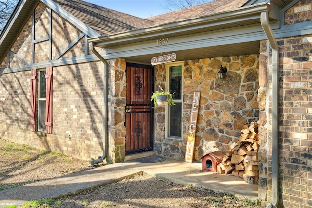 property entrance with stone siding and a shingled roof