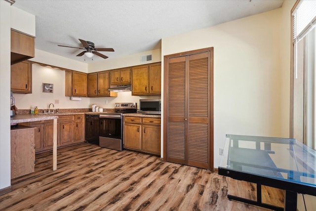 kitchen featuring visible vents, brown cabinets, a ceiling fan, under cabinet range hood, and appliances with stainless steel finishes