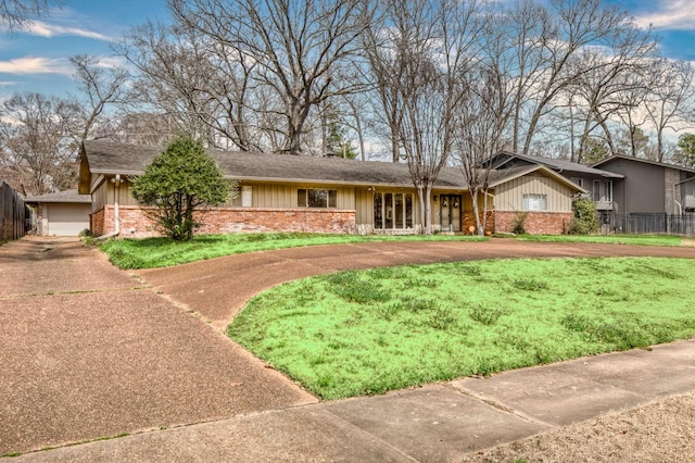 single story home featuring curved driveway, board and batten siding, a front lawn, and fence