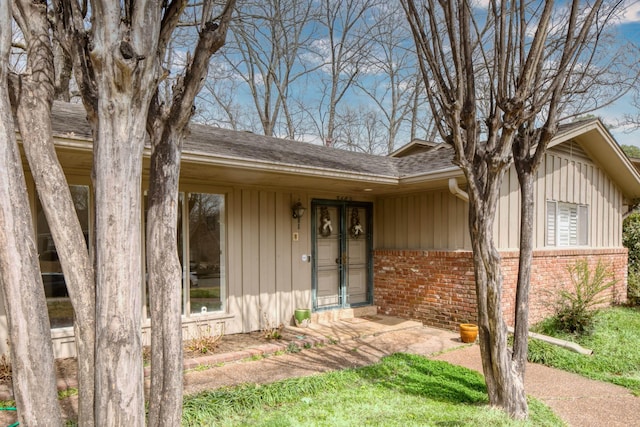 entrance to property with brick siding and roof with shingles