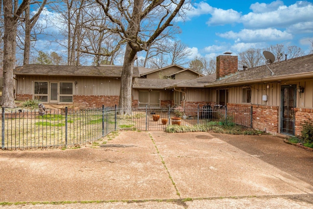 exterior space featuring brick siding, board and batten siding, a shingled roof, fence, and a chimney