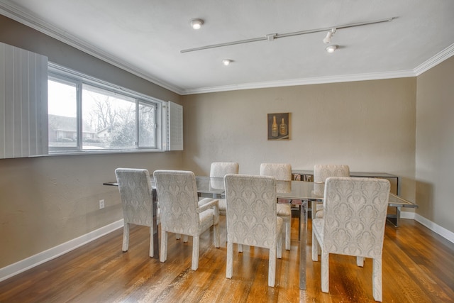 dining space with track lighting, wood finished floors, baseboards, and ornamental molding