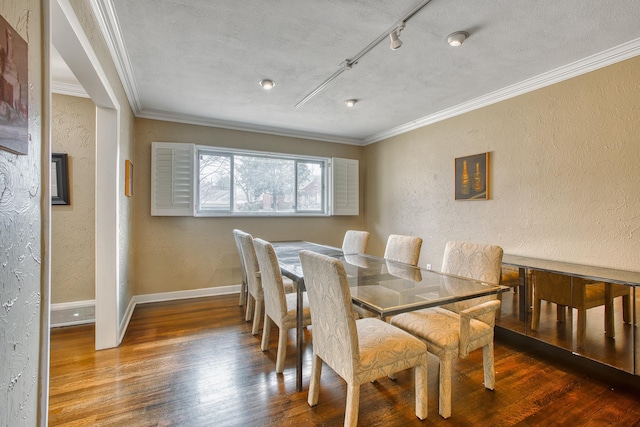 dining area featuring wood finished floors, ornamental molding, and a textured wall