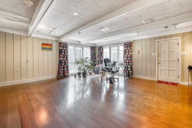 misc room featuring beamed ceiling, baseboards, a textured ceiling, and wood finished floors