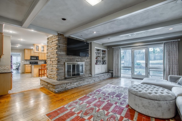 living room with beamed ceiling, light wood-style floors, and a fireplace