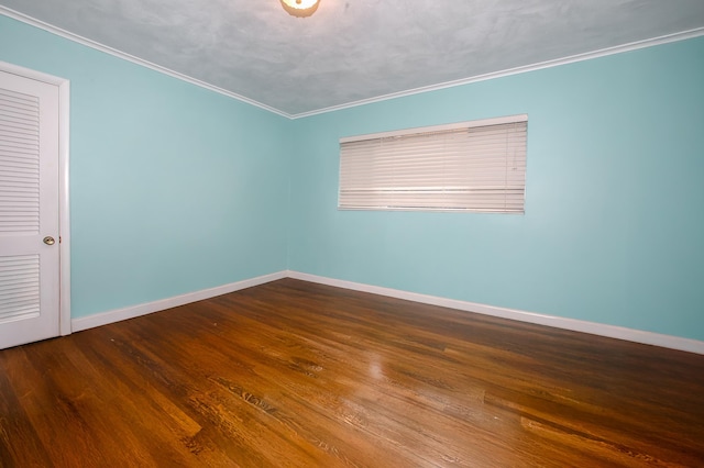 unfurnished room featuring dark wood finished floors, crown molding, and baseboards