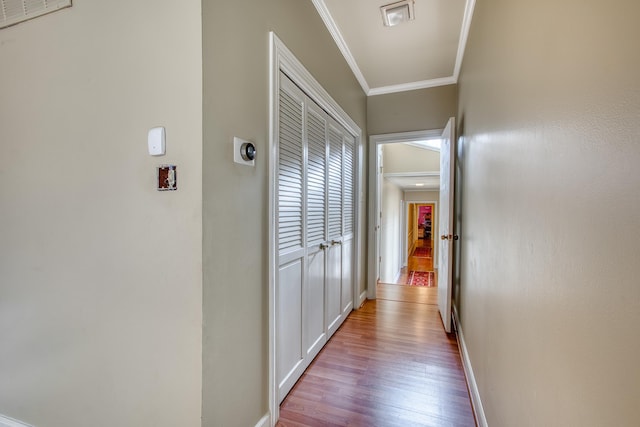 hall featuring wood finished floors, baseboards, and ornamental molding