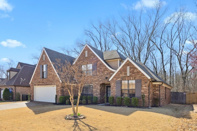 view of front facade with brick siding, a front lawn, fence, concrete driveway, and a garage