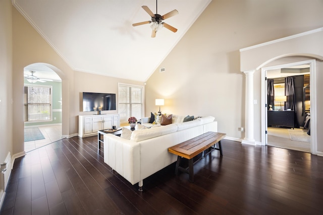 living room with arched walkways, dark wood-style floors, a ceiling fan, and decorative columns