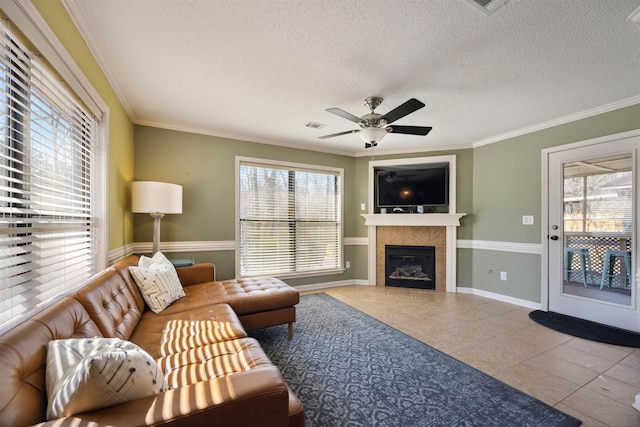 living room with tile patterned floors, ceiling fan, a fireplace, and ornamental molding