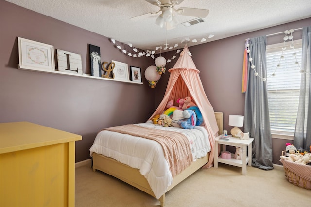 carpeted bedroom featuring baseboards, a ceiling fan, visible vents, and a textured ceiling