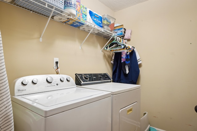 clothes washing area featuring a textured ceiling, washing machine and dryer, and laundry area