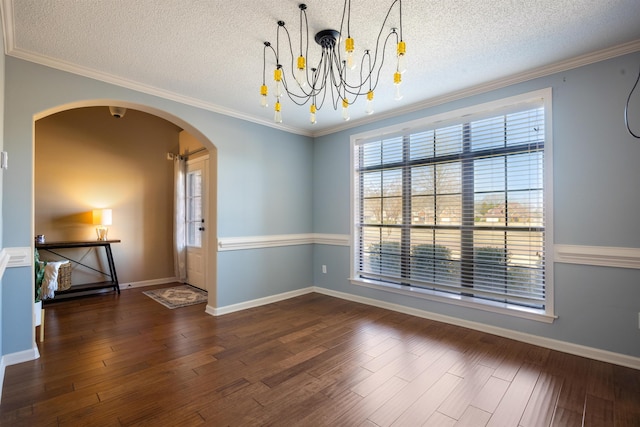 spare room featuring crown molding, wood finished floors, arched walkways, and a chandelier