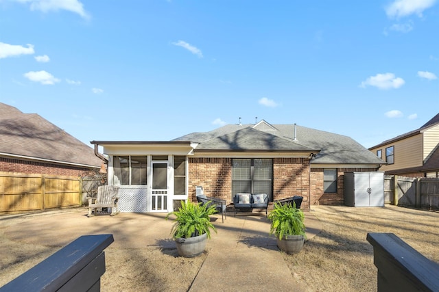 rear view of house with brick siding, a shingled roof, a fenced backyard, a sunroom, and a patio area