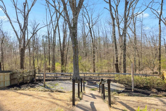 view of yard with a wooded view and fence