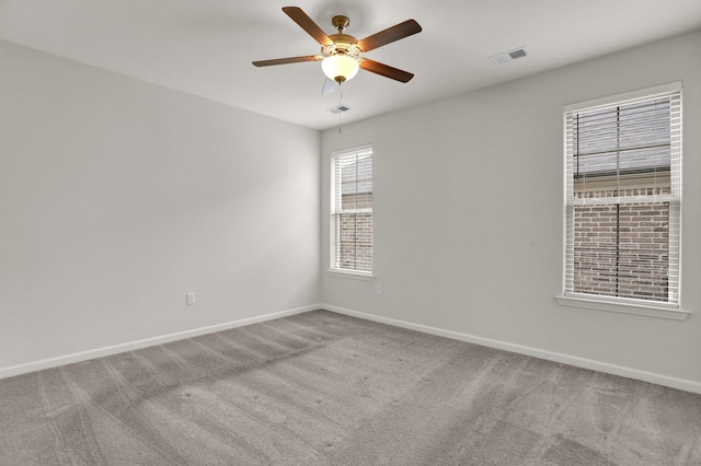 empty room with carpet flooring, baseboards, visible vents, and ceiling fan