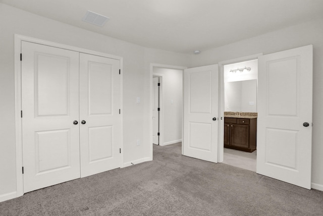 unfurnished bedroom with visible vents, baseboards, carpet floors, ensuite bathroom, and a closet