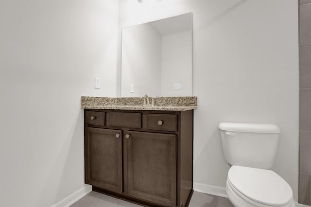 bathroom with vanity, toilet, baseboards, and tile patterned flooring